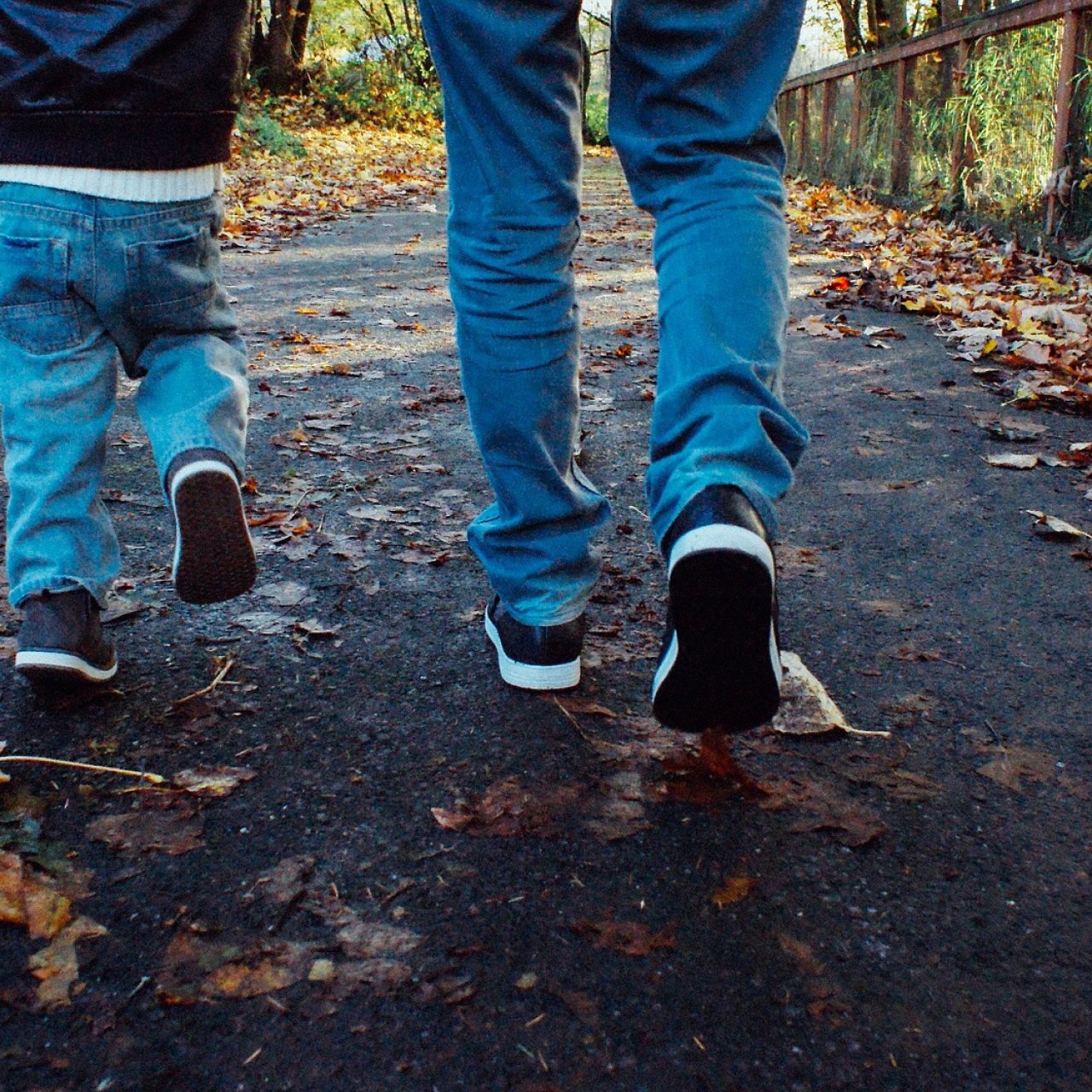 Vater und Sohn laufen im Wald, es ist Herbst und Laub liegt am Boden.