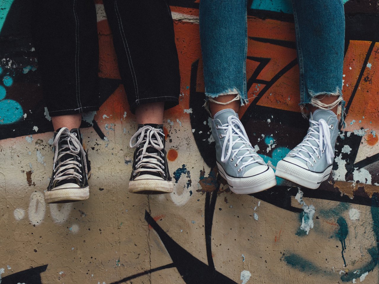 zwei Teenies sitzen auf einer Mauer